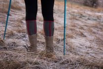 Baixa seção de mulher de pé com poste de caminhada durante o inverno — Fotografia de Stock