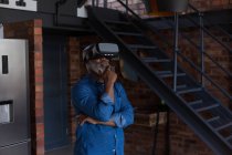 Homem sênior usando fone de ouvido de realidade virtual em casa — Fotografia de Stock