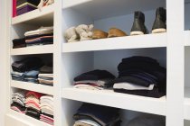 Clothes and shoes kept in shelves at home — Stock Photo