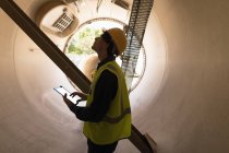 Рабочий мужчина, использующий цифровой планшет при осмотре бетонного тоннеля на солнечной станции — стоковое фото