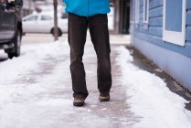 Low section of man walking on sidewalk during winter. — Stock Photo