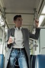 Homem pensativo com xícara de café de pé no ônibus — Fotografia de Stock