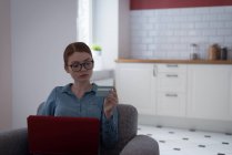 Женщина делает онлайн покупки на ноутбуке с кредитной картой дома — стоковое фото