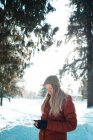 Жінка в зимовому одязі за допомогою мобільного телефону в сонячний день — стокове фото