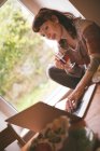 Mulher usando laptop enquanto toma uma xícara de chá em casa — Fotografia de Stock