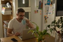 Mann trinkt Kaffee, während er zu Hause Laptop benutzt — Stockfoto