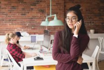 Weibliche Führungskraft telefoniert, während Kollegen im Hintergrund im Büro arbeiten — Stockfoto