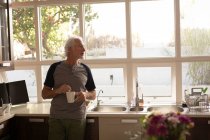 Старший чоловік має каву на кухні вдома — стокове фото