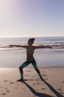 Подходящая женщина выполняет упражнение на растяжку на пляже в сумерках . — стоковое фото
