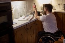Disabled man repairing a pan in kitchen at home — Stock Photo