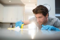 Jeune homme nettoyage cuisine plan de travail à la maison — Photo de stock