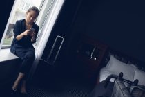 Femme utilisant le téléphone portable dans la chambre d'hôtel — Photo de stock