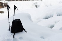 Sac à dos avec bâtons de ski sur un paysage enneigé en hiver — Photo de stock