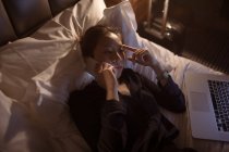 Жінка розмовляє на мобільному телефоні, розслабляючись на ліжку — стокове фото