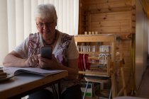 Активная пожилая женщина с мобильного телефона в магазине — стоковое фото