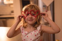 Girl holding heart shape decoration at home — Stock Photo