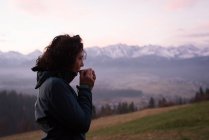 Mujer pensativa tomando café en el campo durante el invierno - foto de stock