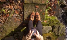 Low section of woman using mobile phone during autumn — Stock Photo