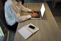 Parte média do homem de negócios usando um laptop na mesa no quarto do hotel — Fotografia de Stock