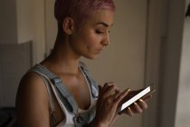 Mujer joven con mensajes de texto de pelo rosa en casa . - foto de stock