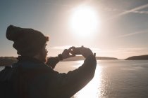 Männlicher Wanderer fotografiert mit Handy in der Nähe des Sees am Land — Stockfoto