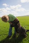 Donna accarezzare il cane nel campo in una giornata di sole — Foto stock