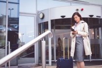 Складні бізнес-леді за допомогою мобільного телефону за межами готелю — стокове фото