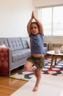 Petite fille effectuant du yoga dans le salon à la maison — Photo de stock