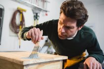 Плотник-мужчина рисует стол в мастерской — стоковое фото