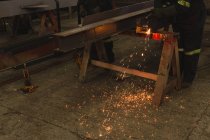 Section basse du soudeur réparant le cadre métallique dans l'atelier — Photo de stock