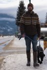 Man walking with dog on sidewalk during winter. — Stock Photo