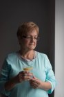 Femme âgée réfléchie ayant du jus de citron à la maison — Photo de stock