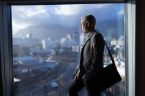 Business man looking outside the window in hotel room — Stock Photo