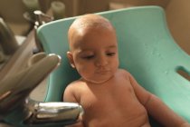 Крупним планом милий маленький дитина лежить в дитячому сидінні для ванни у ванній — стокове фото