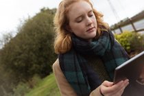 Jeune femme utilisant une tablette numérique dans le parc — Photo de stock