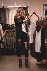 Красивая девушка выбирает одежду из стойки в торговом центре — стоковое фото