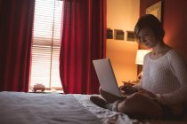 Mulher bonita usando laptop na cama no quarto em casa — Fotografia de Stock