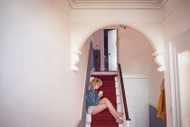 Giovane donna rasatura caffè sulle scale a casa — Foto stock