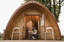Happy couple having coffee at the entrance of log cabin — Stock Photo