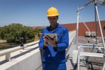 Trabajador masculino usando tableta digital en la estación solar en un día soleado - foto de stock
