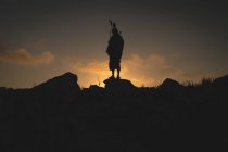 Силует чоловіка-масая, що стоїть на скелі під час сутінків — стокове фото