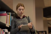 Молода жінка використовує цифровий планшет у бібліотеці — стокове фото