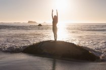 Fit femme effectuant du yoga à la plage au crépuscule
. — Photo de stock