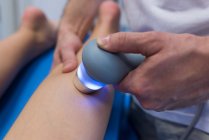 Fisioterapeuta dando massagem nas pernas para mulher com máquina na clínica — Fotografia de Stock