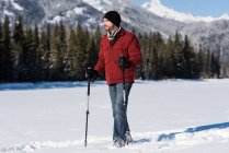 Mann läuft mit Skistöcken in verschneiter Landschaft. — Stockfoto