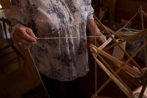 Mid section of woman using weaving loom at shop — Stock Photo