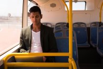 Молодой бизнесмен пользуется ноутбуком во время поездки на автобусе — стоковое фото
