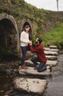Homme proposant femme sur rocher dans la rivière — Photo de stock