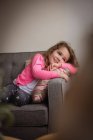 Усміхнена дівчина розслабляється на дивані у вітальні вдома — стокове фото