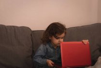 Kleines Mädchen benutzt Laptop im Wohnzimmer zu Hause. — Stockfoto